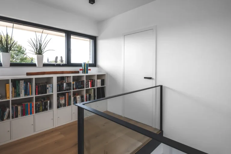 Weiße flächenbündige vitaDOOR Innentür mit schwarzem Türgriff in einem modernen Flur