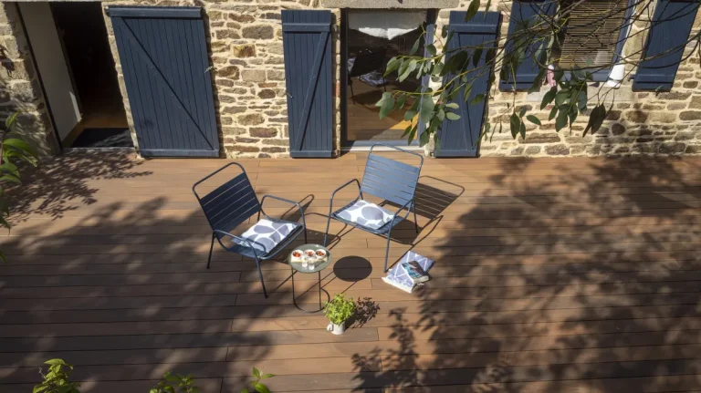 Silvadec Atmosphere WPC-Terrasse in Ipé-Optik mit Sitzplatz vor einem Natursteinhaus