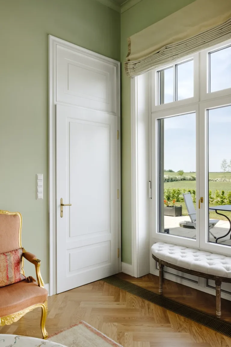 Weiße klassische Innentür von Brüchert + Kärner in einem hellen Wohnraum mit großen Fenstern